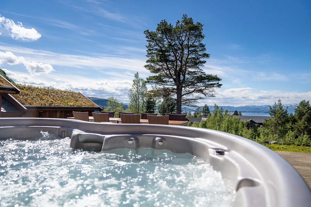 Outdoor jacuzzi at Alten Lodge with views over the fjord and surrounding forest.