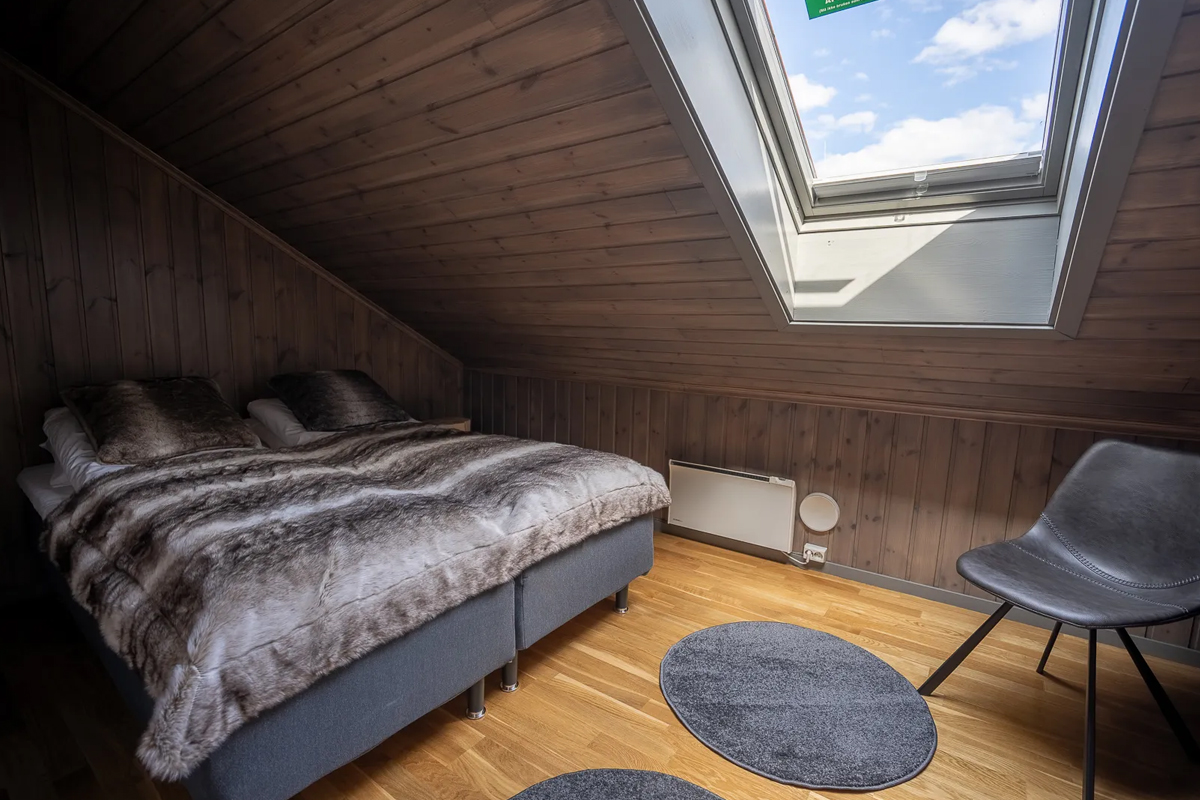 Attic bedroom at Alten Lodge with a skylight window and faux fur bedding.