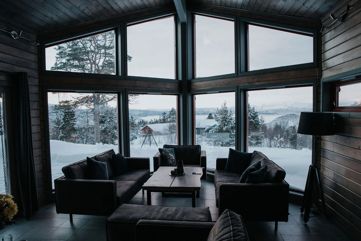 Main cabin lounge at Alten Lodge with floor to ceiling windows overlooking snowy scenery.