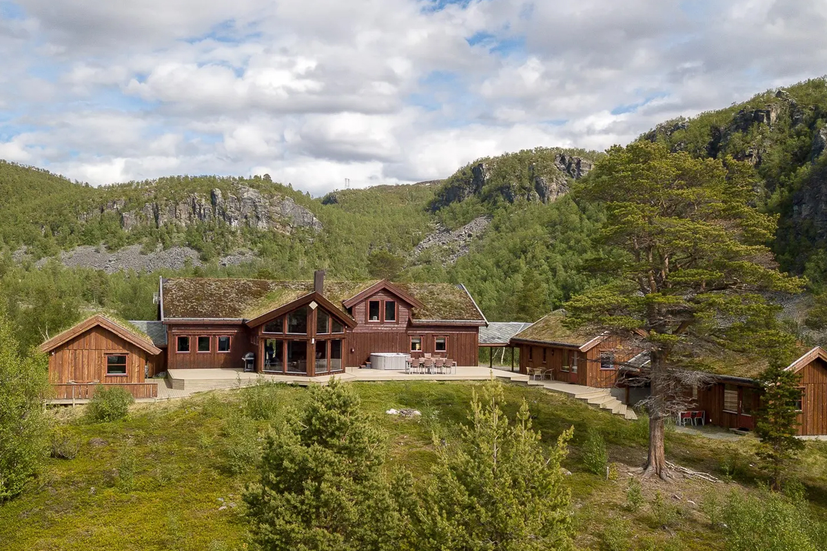 Aerial view of Alten Lodge and its turf roofed cabins surrounded by green hills.