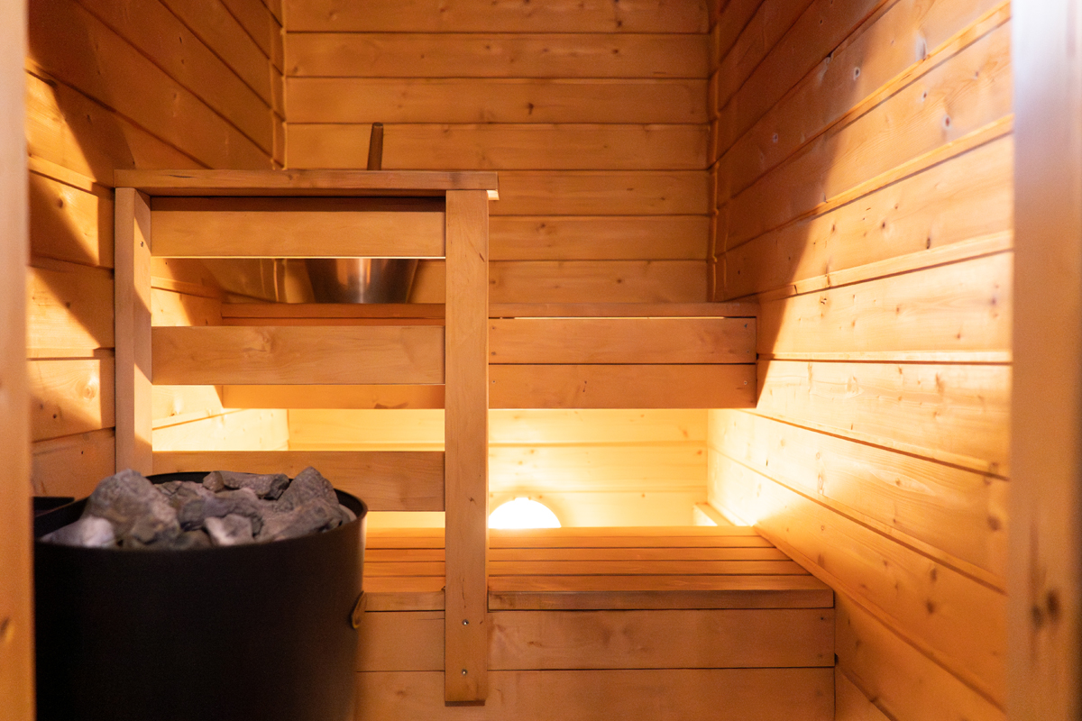 Traditional wood fired sauna at Alten Lodge with heated stones and warm lighting.