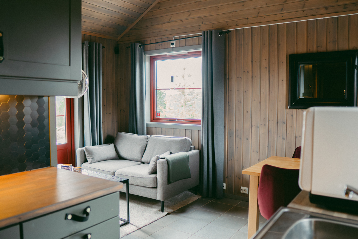Living room in a small cabin at Alten Lodge with wood paneled walls and soft seating.