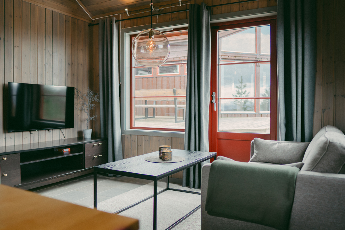 Living room in a small cabin at Alten Lodge with a red framed door leading outside.