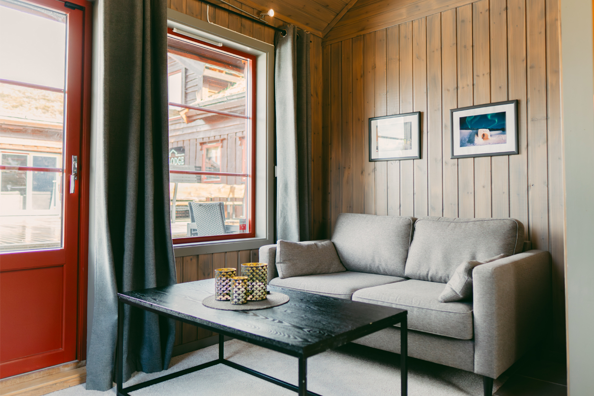 Living room in a small cabin at Alten Lodge with framed photos and a red door.