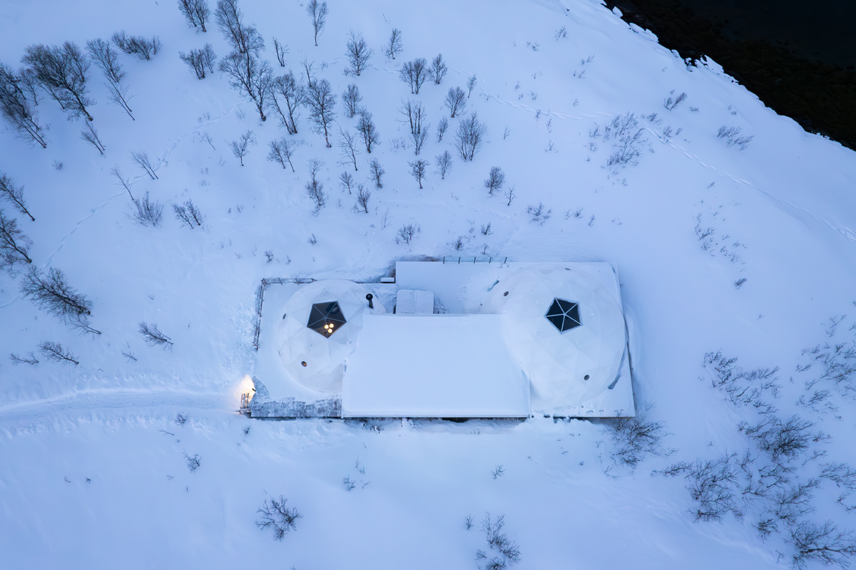 Aerial view of a twin-dome igloo cabin at Isbreen surrounded by snow-covered terrain.