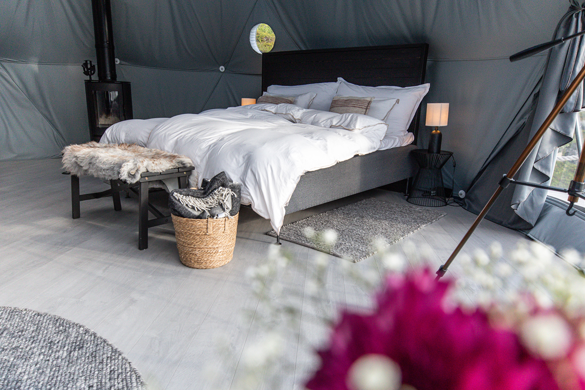 Bedroom inside a dark-toned igloo at Isbreen with a wood stove and soft furnishings.