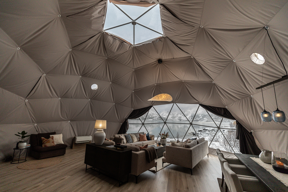 Living area inside a spacious igloo at Isbreen with skylight and panoramic fjord views.