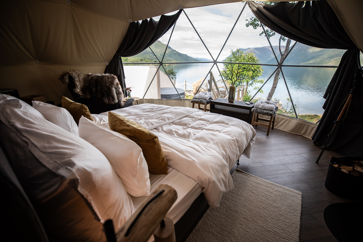 A double bed inside a glass igloo at Isbreen, framed by fjord and mountain views.