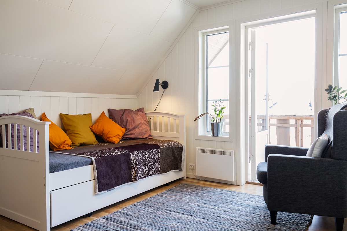 Cozy attic guest room with a daybed and balcony access at Trasti & Trine.
