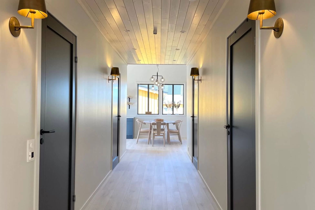 Bright hallway with brass wall lights leading to dining area in a Varanger Brygge property