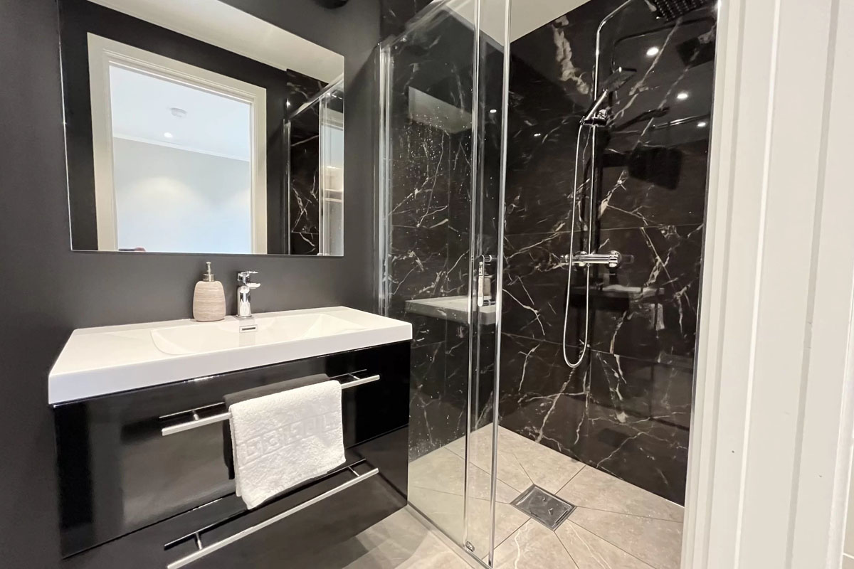 Renovated bathroom with marble shower and black fixtures at Varanger Brygge Bugøynes