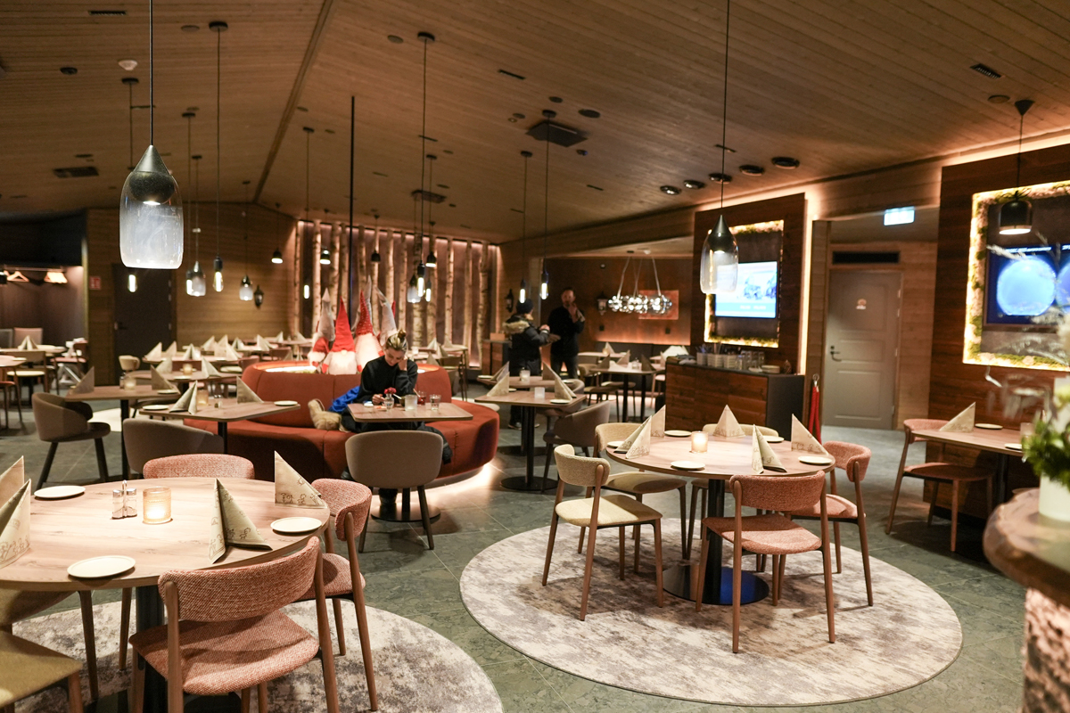 Warm restaurant dining room with round tables, pendant lights and Nordic decor, Aurora Village, Ivalo