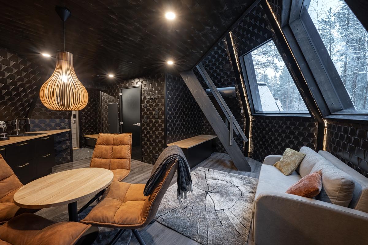Tower suite living area with sofa, dining table and kitchenette under a wood pendant light, Aurora Village, Ivalo