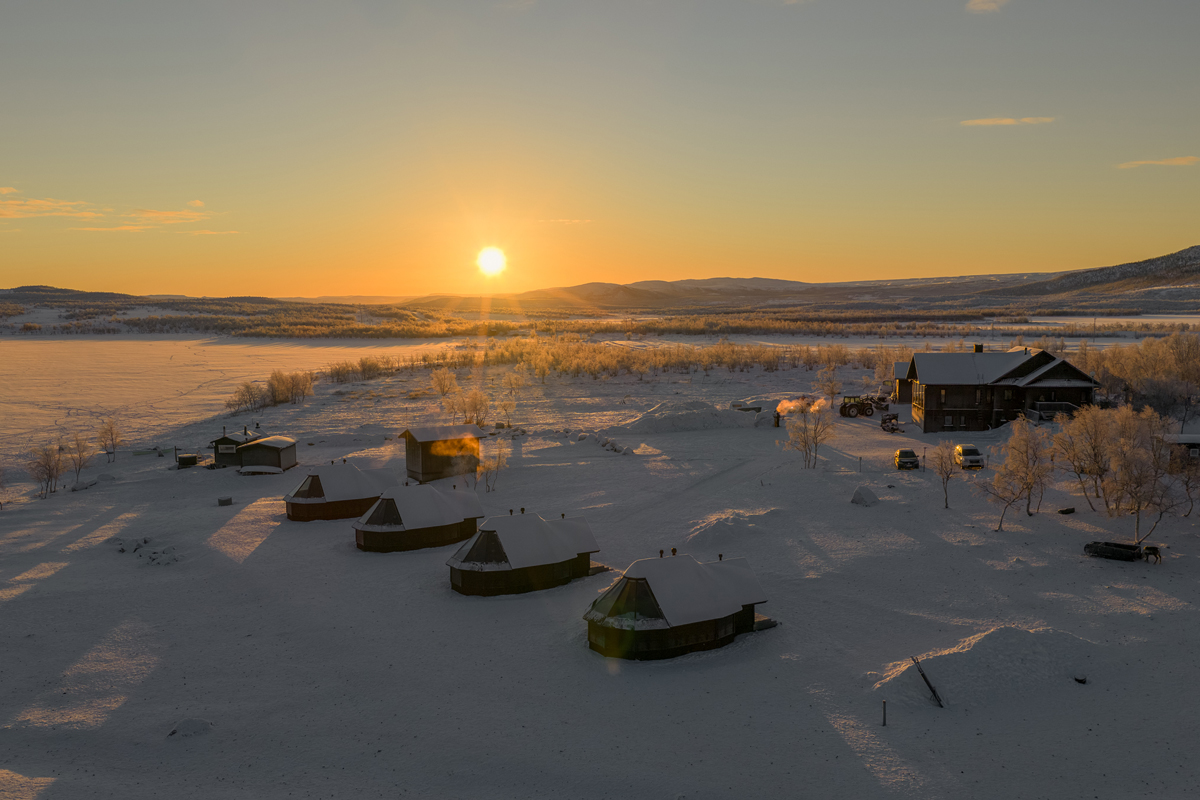 Aerial view of glass igloo cabins and the main lodge at sunrise at Arctic Land Adventure, Kilpisjärvi.