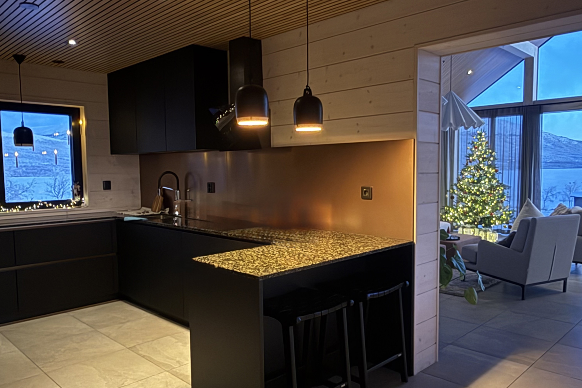 The modern kitchen at Villa Vasara opens to a lit Christmas tree and lake view at dusk, Kilpisjärvi.