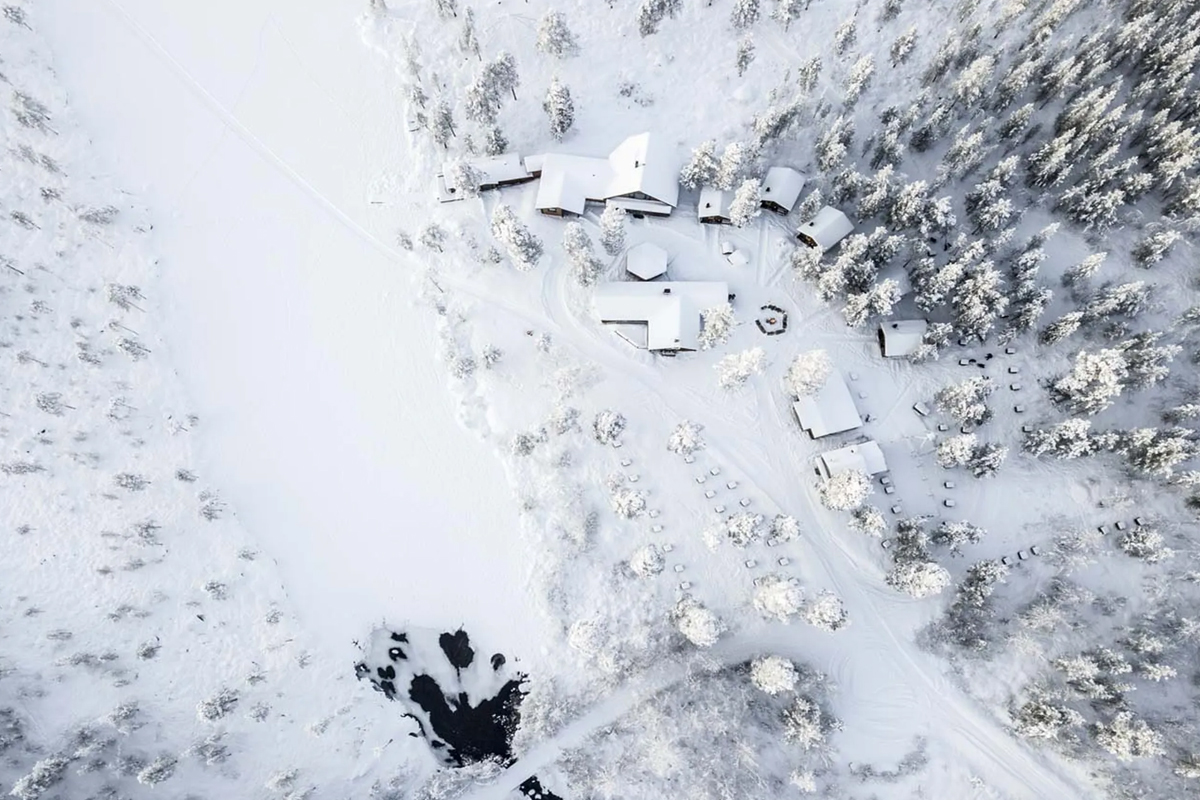 Aerial view of the snow-covered Fjellborg Arctic Lodge property with cabins and trails in Kiruna.