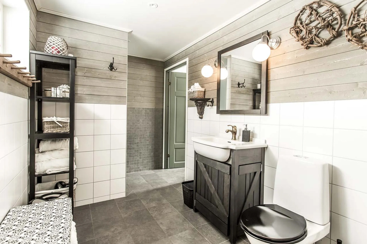 A tiled bathroom with a wood-front vanity and walk-in shower at Fjellborg Arctic Lodge, Kiruna.