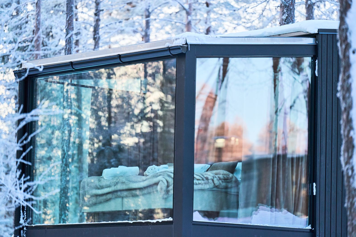Bed seen through the glass wall of a Glass Igloo at Balder Luxury Lodge in Levi.