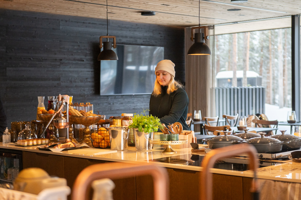 Staff preparing a breakfast buffet counter with fresh produce, pastries and copper fittings, Olo Resort, Levi