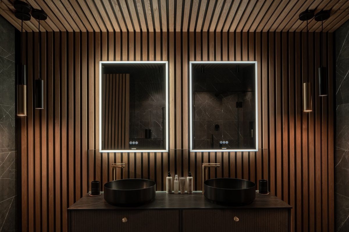 A modern double vanity with wood-slat walls and black round sinks in a Loggers Lodge bathroom.