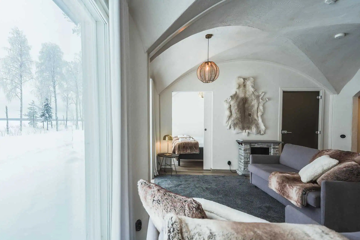 Living room in the Lakeview Suite at Apukka Resort with snowy forest views through the window.