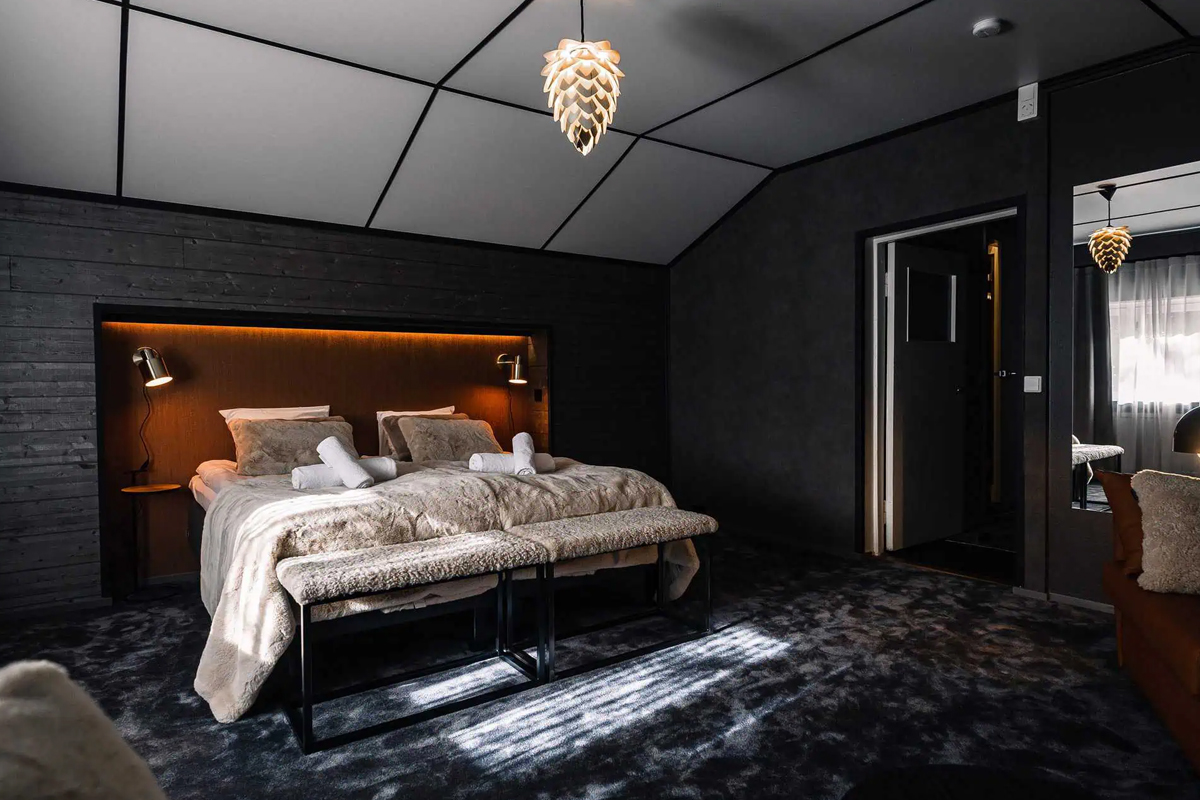 Bedroom in Villa Apukka at Apukka Resort with a fur throw and warm bedside lighting.