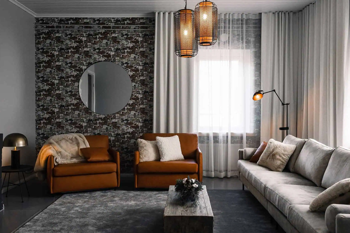 Living room in Villa Apukka at Apukka Resort with leather armchairs and a round mirror.