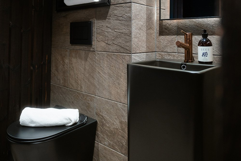 Igloo bathroom with dark stone tiles, a black basin, copper tap and premium toiletries, Halo Igloos, Rovaniemi