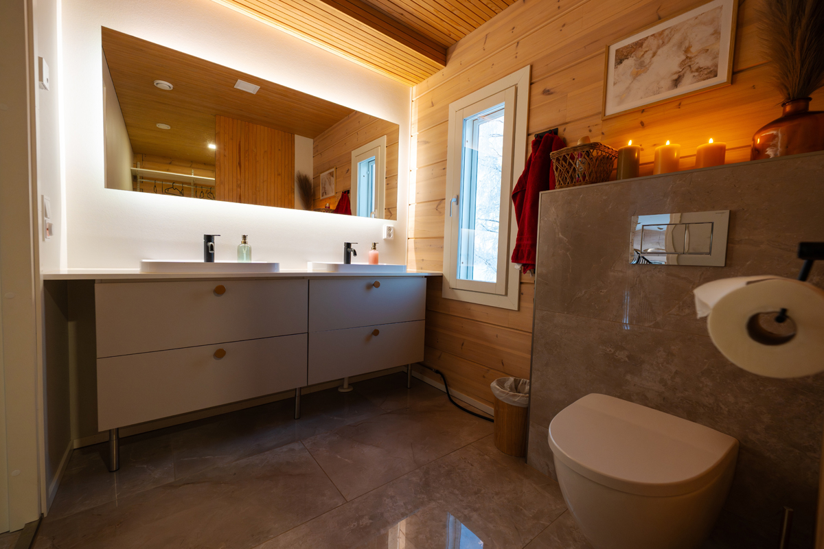 Salle de bain de la villa avec double vasque, sol en marbre et éclairage chaleureux.