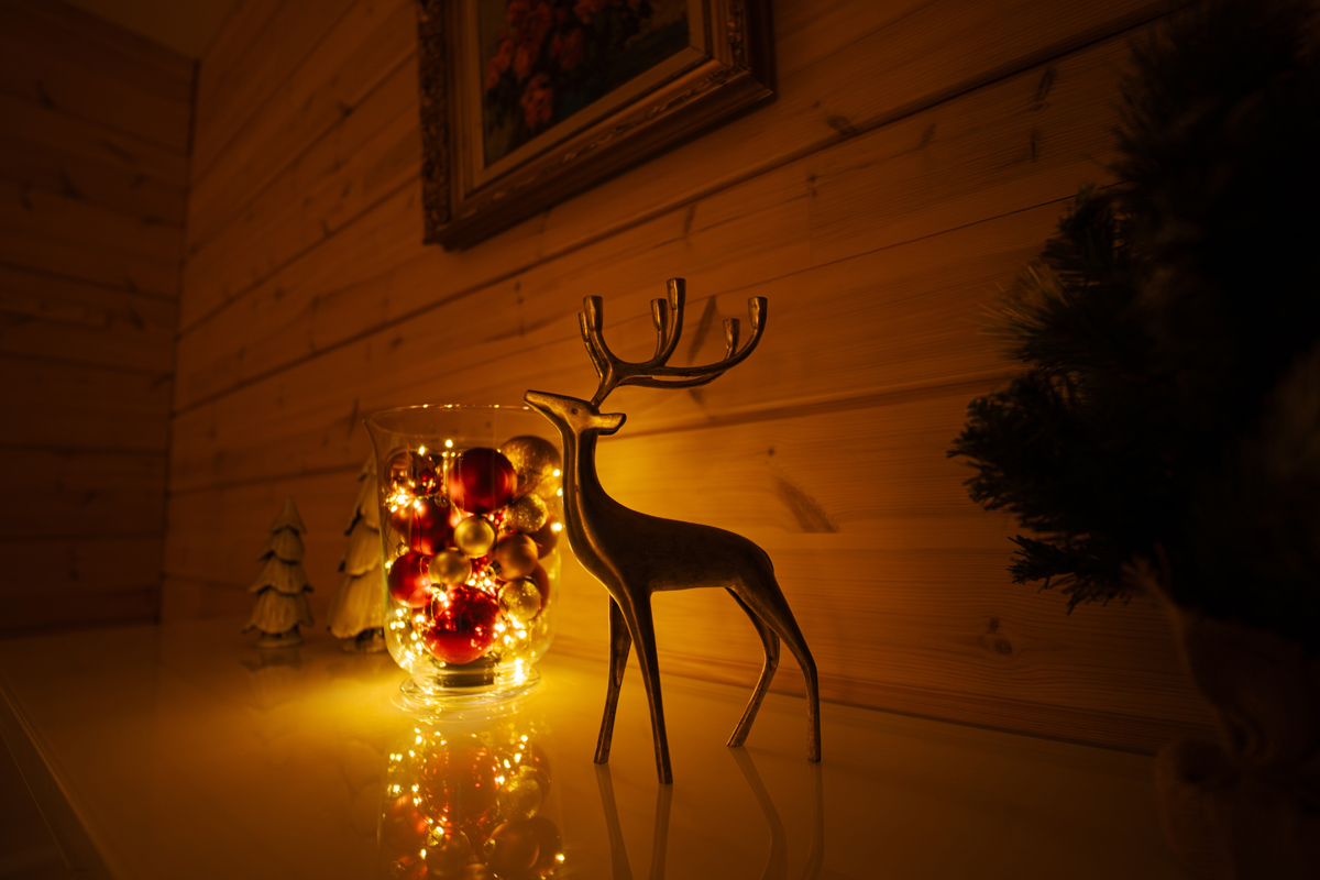 Décoration de Noël avec un renne et un bocal de boules lumineuses sur une étagère en bois.
