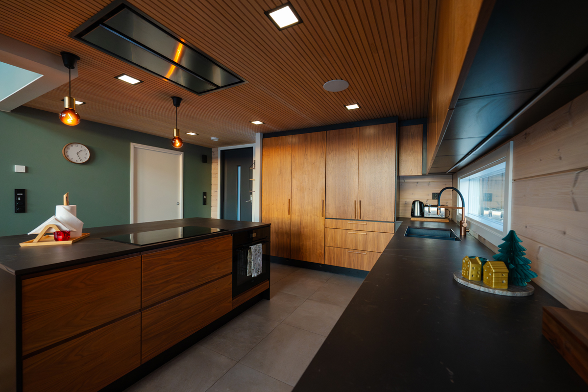 Cuisine de la villa avec îlot central au plan de travail sombre et rangements en bois.