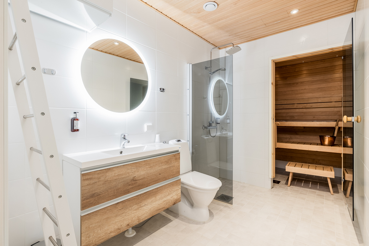 Bright bathroom with a round backlit mirror, walk-in shower and a private Finnish sauna, Santa Claus Holiday Village, Rovaniemi