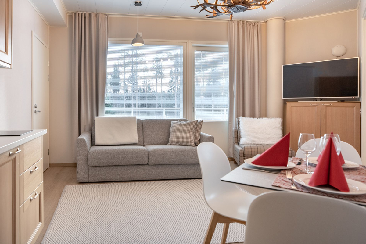 Living and dining area of a family suite with sofa, dining table and antler chandelier, Santa Claus Holiday Village, Rovaniemi