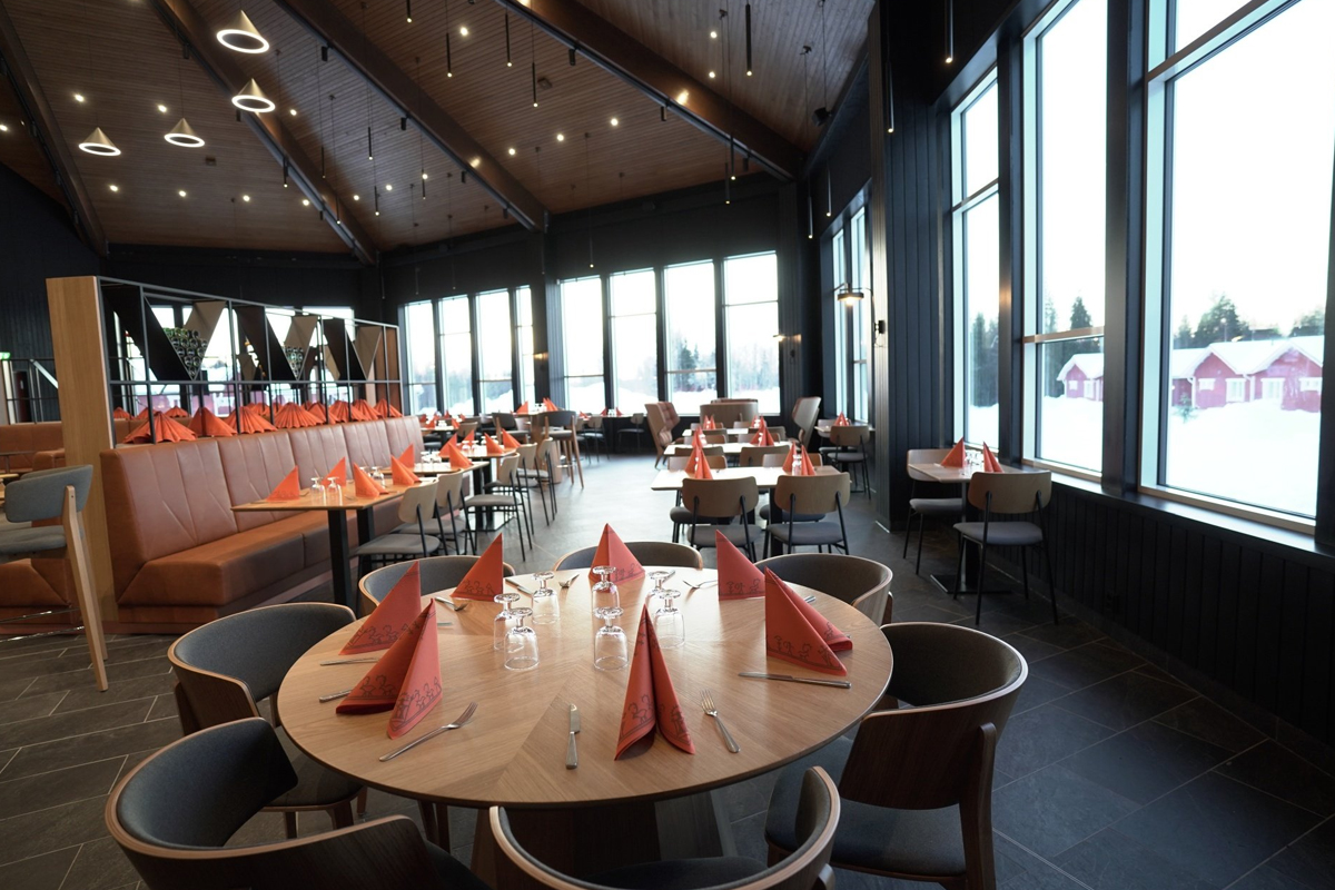 Santa's Cuisine restaurant dining room with wooden tables, orange napkins and snow views, Santa Claus Holiday Village, Rovaniemi