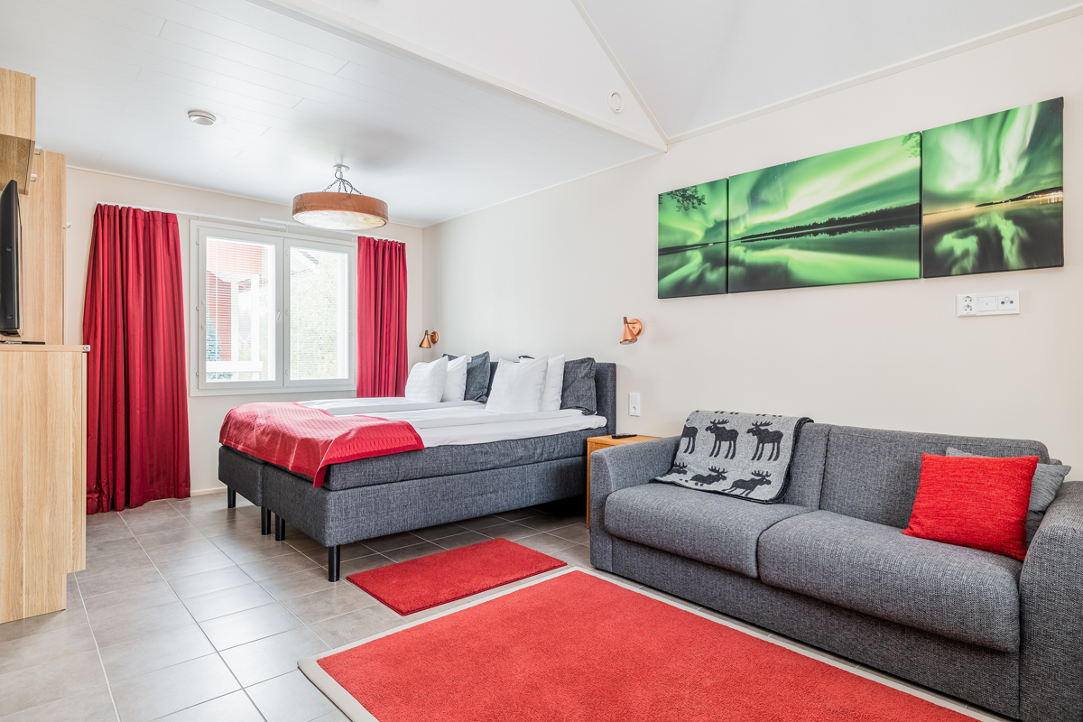 Superior cottage bedroom with a double bed, sofa and northern lights artwork on the wall, Santa Claus Holiday Village, Rovaniemi