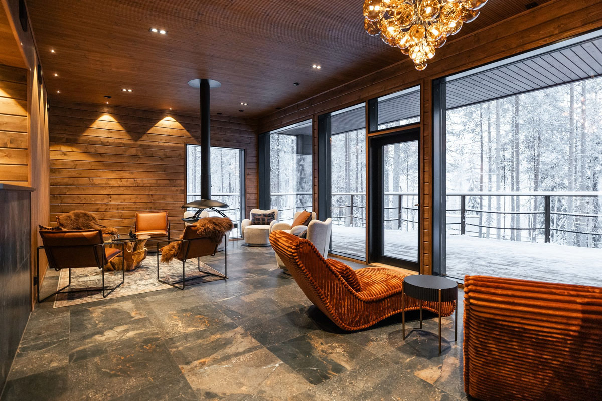 Espace salon du spa nordique du Skýra Retreat, avec baies vitrées donnant sur la forêt et fauteuils aux textures chaleureuses.