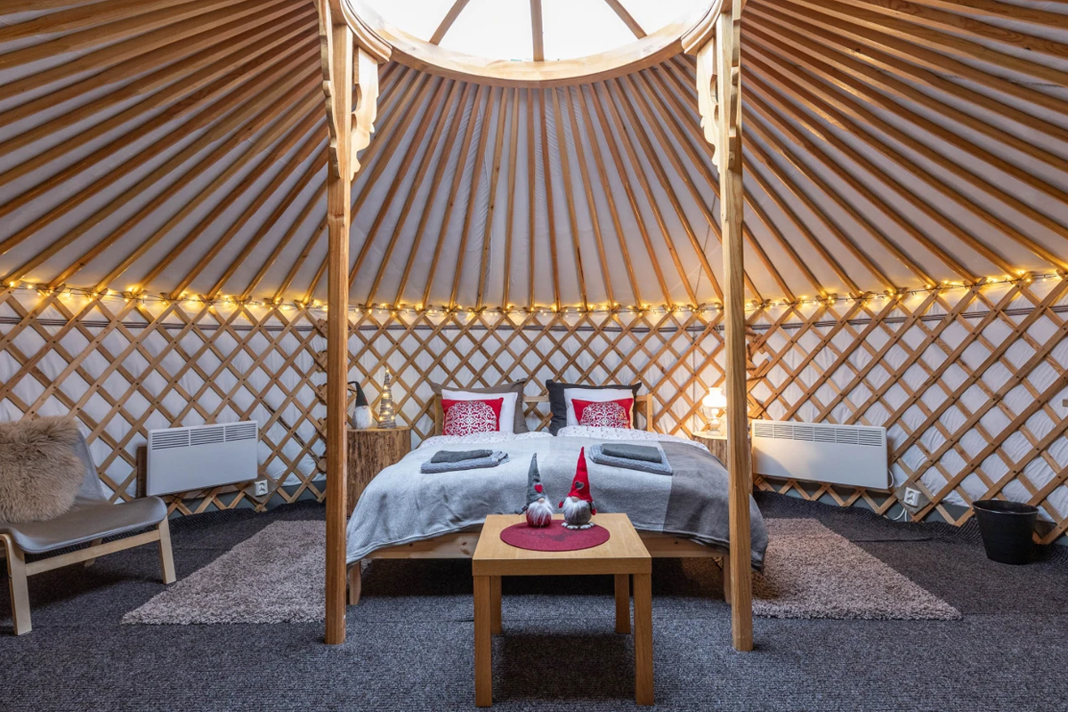 Interior of a yurt at Yurt District with a domed skylight, fairy lights, and a cozy double bed.