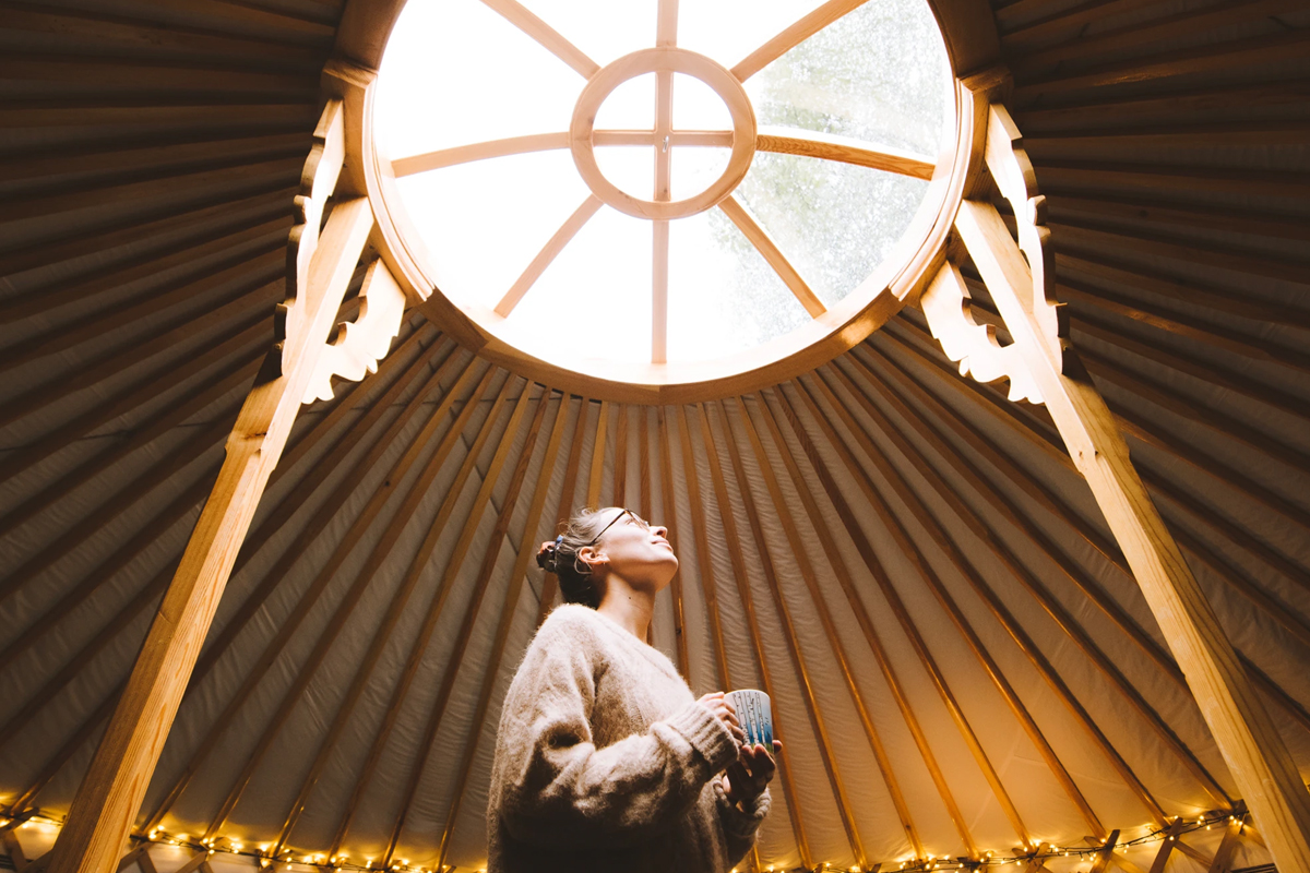 A guest looks up at the domed skylight inside a yurt at Yurt District.