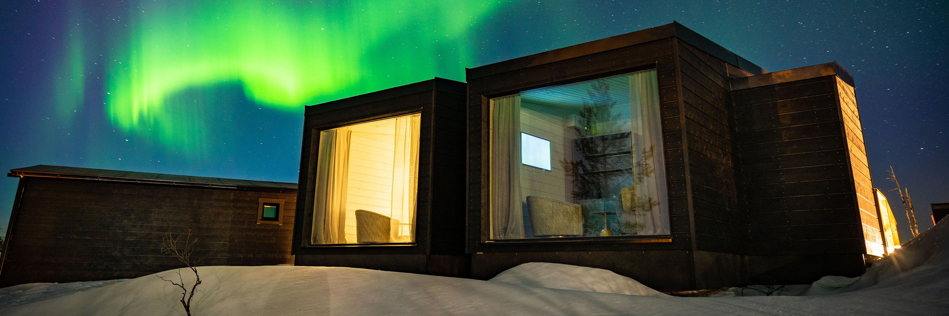 Chalet Aurora Collection avec larges baies panoramiques sous des aurores boréales vertes et ondulantes, Saariselkä