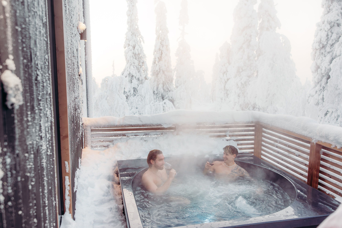 Two guests in a steaming outdoor hot tub surrounded by frosted trees, Aurora Collection, Saariselkä