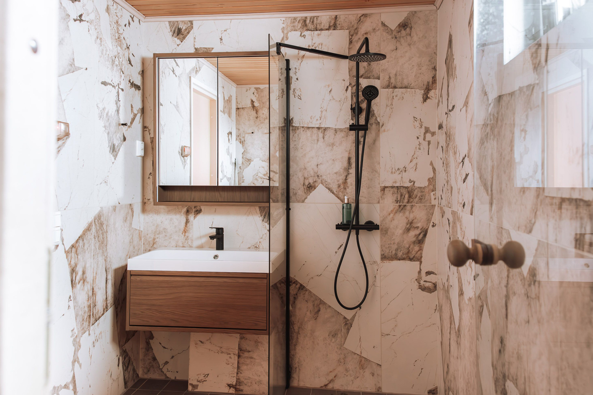 Marble-tiled bathroom with a rain shower and dark wood vanity unit inside an Aurora Collection cabin