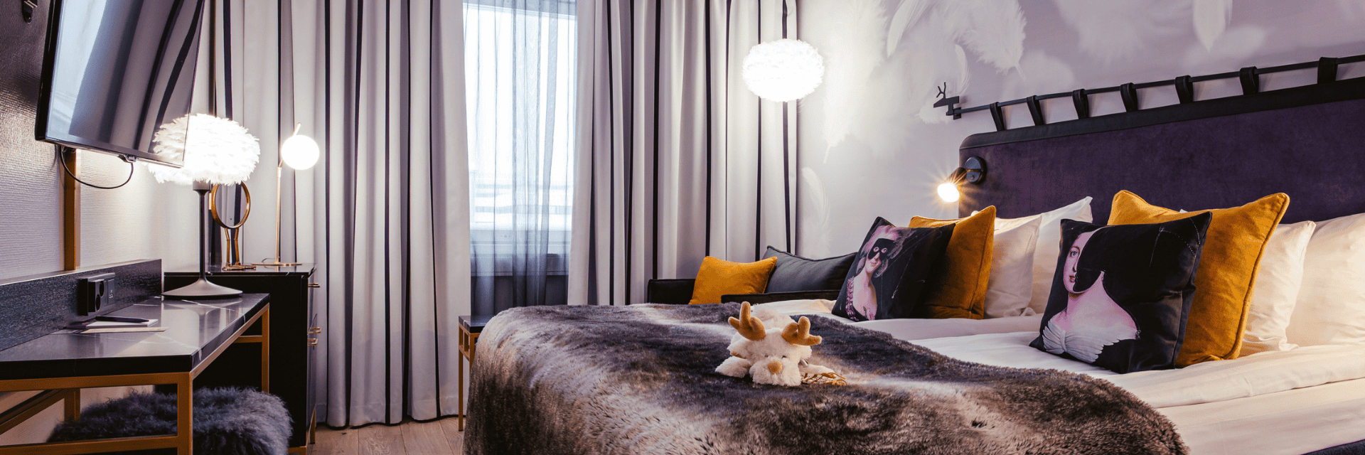 Bedroom at Arctic City Hotel in Rovaniemi with a faux fur throw, mustard cushions, and portrait art.