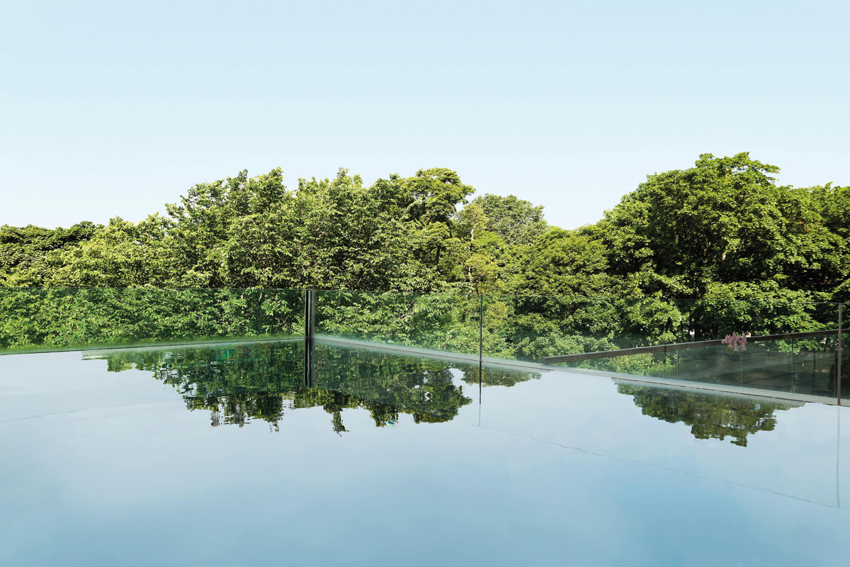 Outdoor pool at the Elements Spa at Clarion Hotel Stockholm in summer, with treetop views and a glass balustrade.