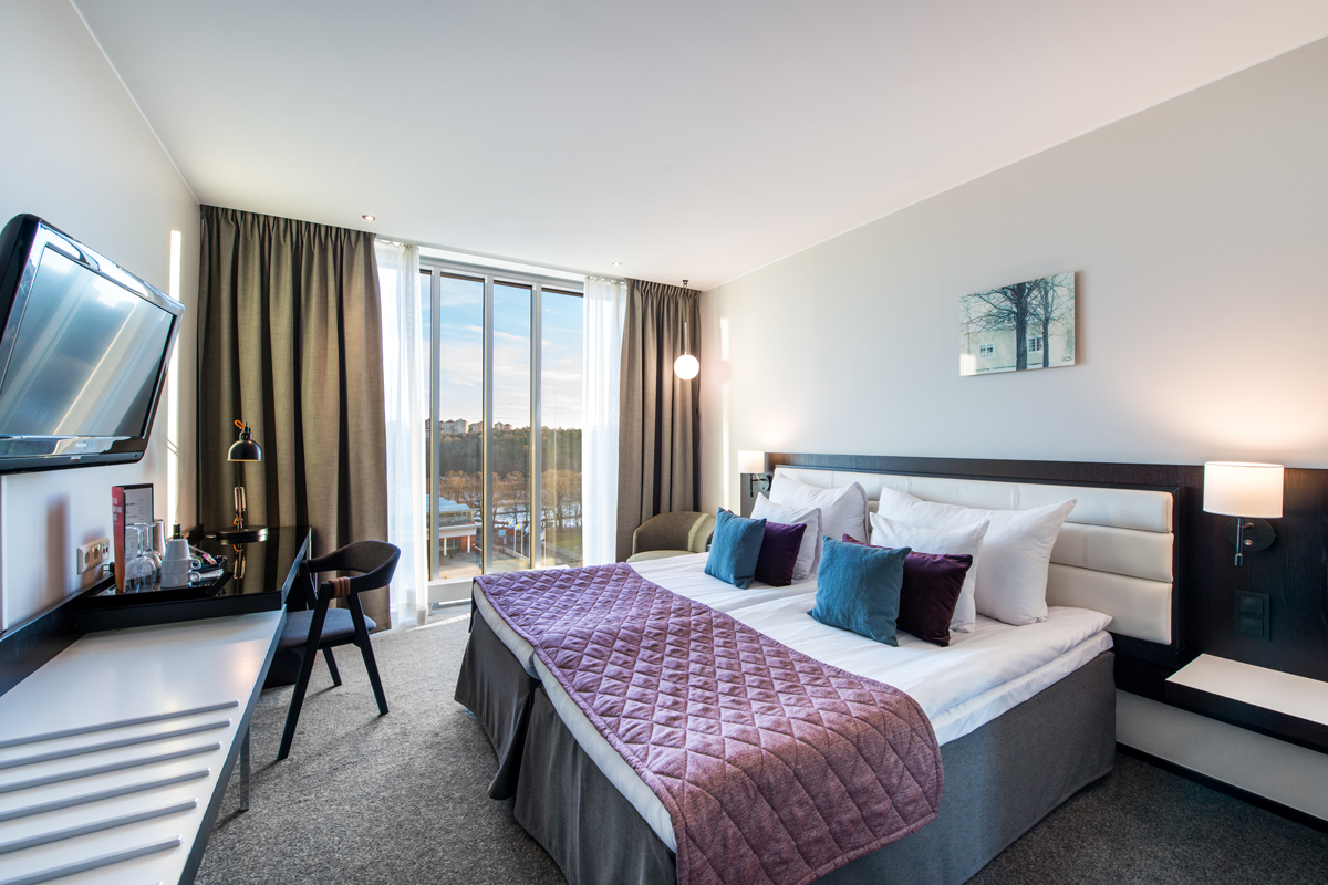Superior twin room at Clarion Hotel Stockholm with a double bed, floor-to-ceiling windows, and views over Södermalm.