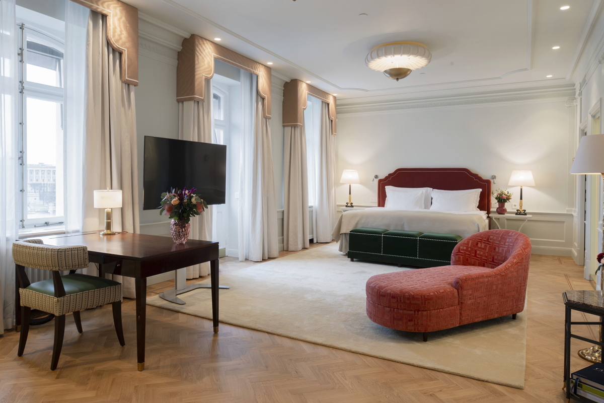 Bedroom of the Bernadotte Suite at Grand Hôtel Stockholm, with a red upholstered king-size bed, parquet flooring, and elegant period furnishings.