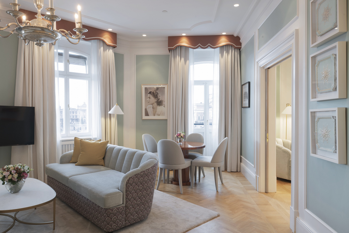 Sitting room and bedroom of a Superior Suite at Grand Hôtel Stockholm, with crystal chandelier, pink accents, and waterfront views.