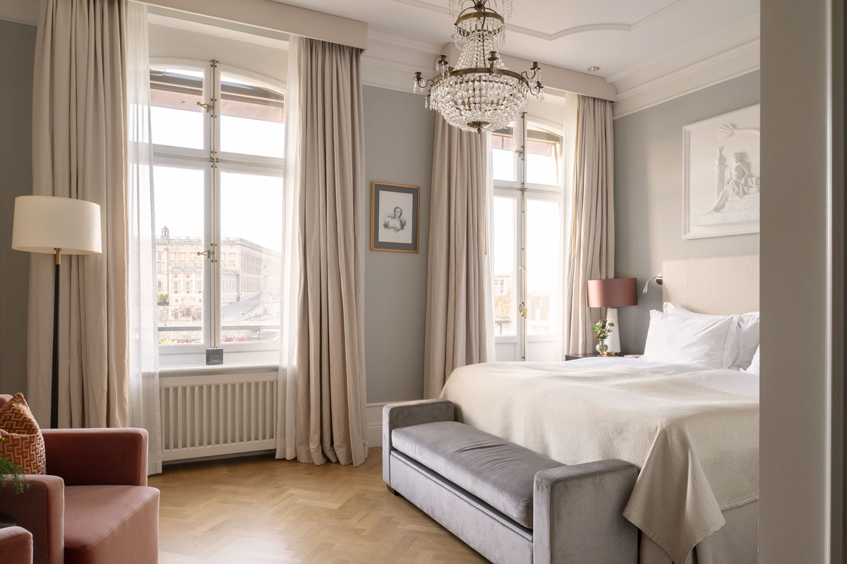 Superior Room at Grand Hôtel Stockholm with a king-size bed, crystal chandelier, and large windows overlooking the Royal Palace.