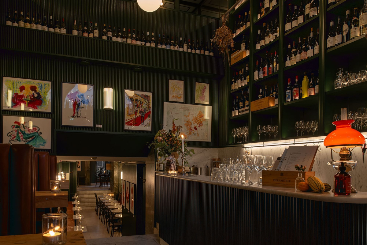 Wine bar at The Sparrow Hotel in Stockholm, with floor-to-ceiling wine racks, marble counter, candlelight, and French artwork on the walls.