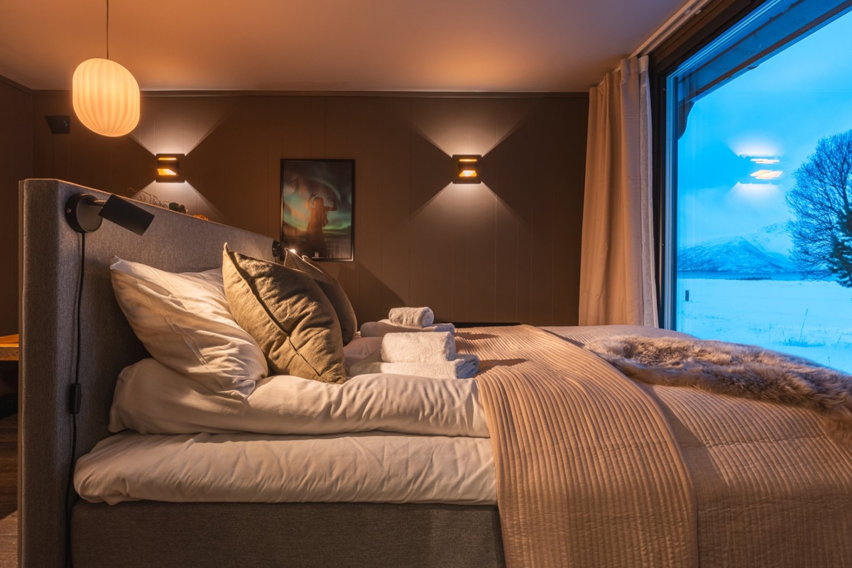 Bed inside an Aurora Glass Cabin at Aera in Tromso, in the evening light.