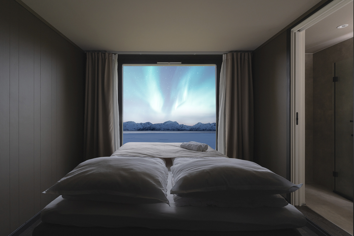 Bed facing the northern lights inside an Aurora Glass Cabin at Aera.